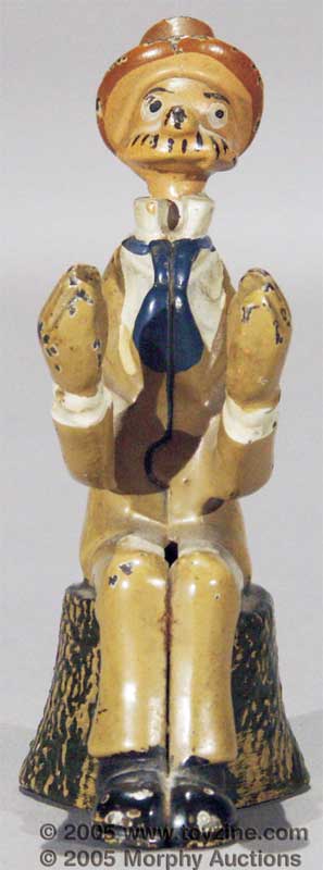 Wonderful 4&frac12;in Andy Gump figural still bank depicting the classic comic character seated on a tree stump